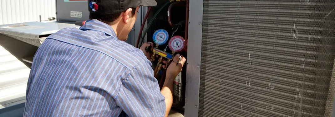HVAC technician servicing a condenser unit in Orleans